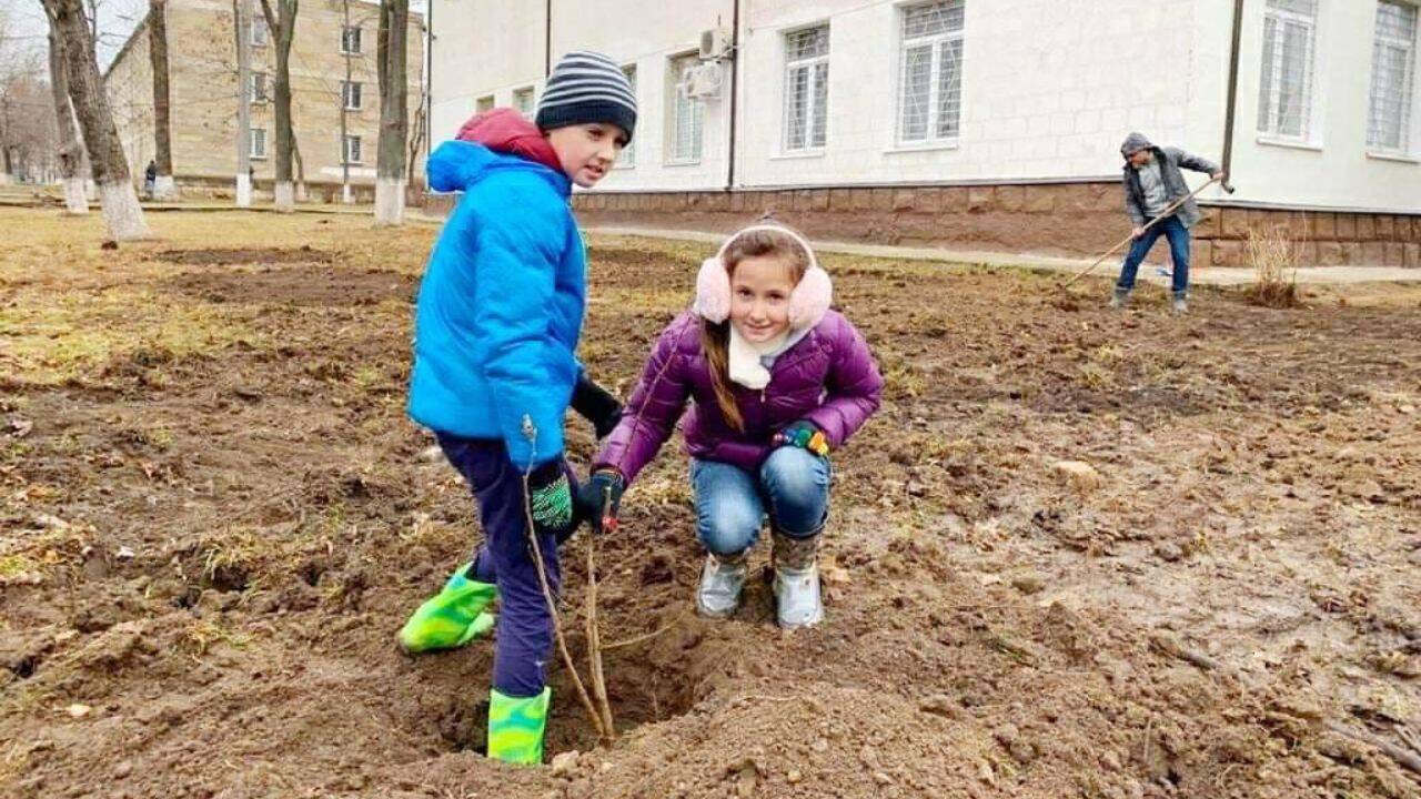 doi copii plantand un pom